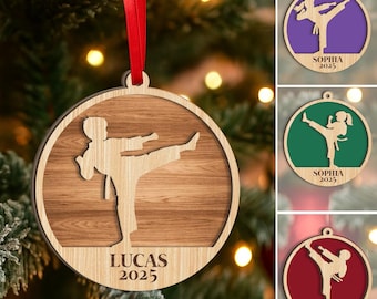 May include: Wooden Christmas ornament featuring a karate figure in a kicking pose. The ornament has a circular design with a wood grain background and the name "LUCAS 2025" printed at the bottom. A red ribbon is attached for hanging.