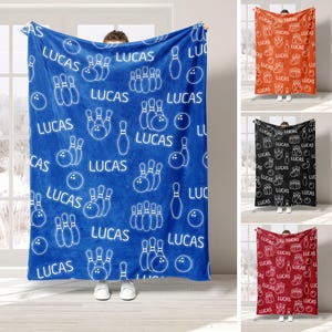 May include: A blue fleece blanket with a white bowling pin and ball pattern. The blanket has the name "Lucas" repeated throughout the pattern.