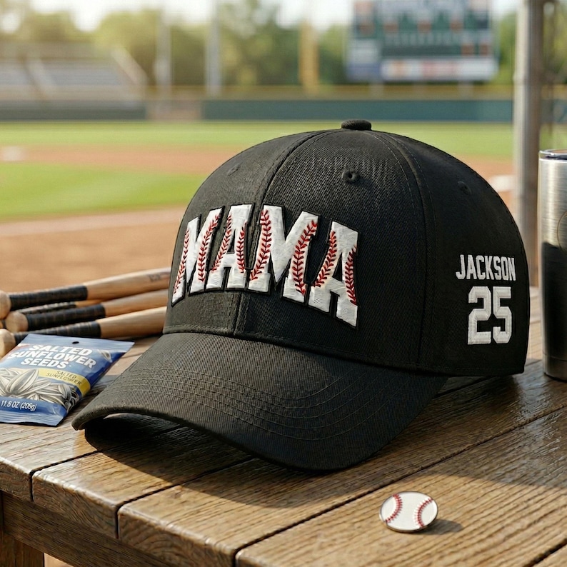 以下が含まれることがあります： 白と赤の野球のステッチが入った「MAMA」という文字が入った黒い野球帽。 「Jackson」という名前と数字の「25」が側面にあります。 野球をテーマにしたピンとヒマワリの種の袋が木製の表面にあります。