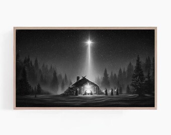 Pode incluir: Impressão emoldurada em preto e branco de uma cena de inverno. Uma estrela brilhante brilha sobre uma pequena cabana, com figuras reunidas dentro. Árvores escuras de folhas perenes cercam a cabana, sob um céu estrelado.