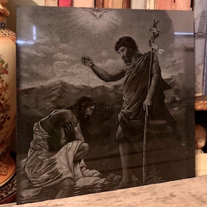 May include: A black and white engraving of a religious scene depicting a man being baptized by another man in a river. The man being baptized is kneeling in the water, while the other man is standing and pouring water over his head. A dove is flying above them.