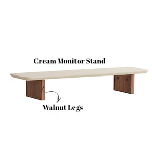 Puede incluir: Soporte de monitor color crema con patas de nogal. El soporte tiene una parte superior rectangular y dos patas rectangulares. El texto "Cream Monitor Stand" y "Walnut Legs" son visibles en la imagen.