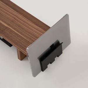 May include: A wooden laptop stand with a black laptop holder. The laptop is closed and the stand is on a white surface.