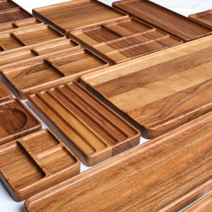 May include: A set of wooden trays in various sizes and with compartments. The trays are made from light brown wood with a natural grain pattern.