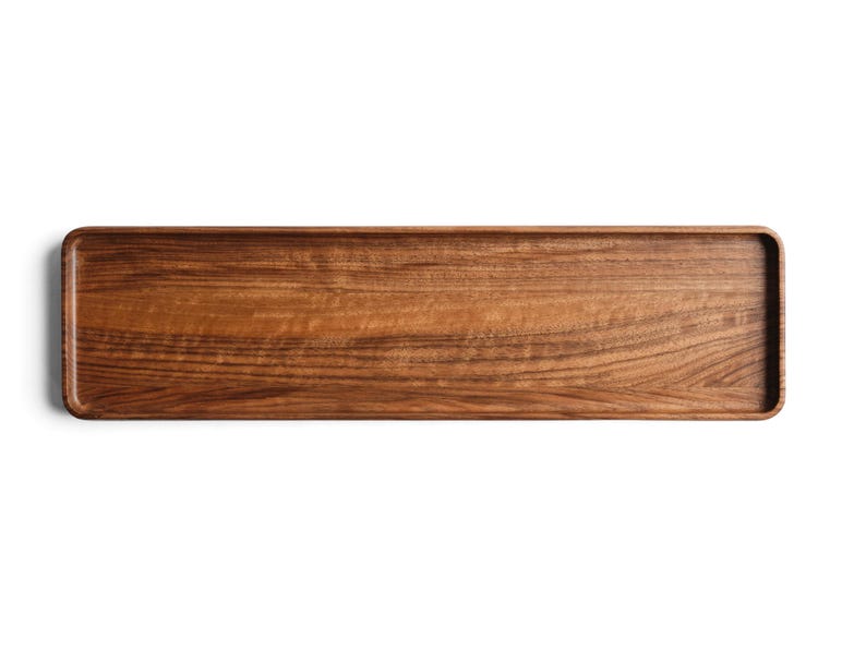 May include: A rectangular wooden tray with a smooth, polished finish and visible natural grain patterns. The tray features slightly raised edges and rounded corners, showcasing a rich, warm brown color throughout the entire surface area.