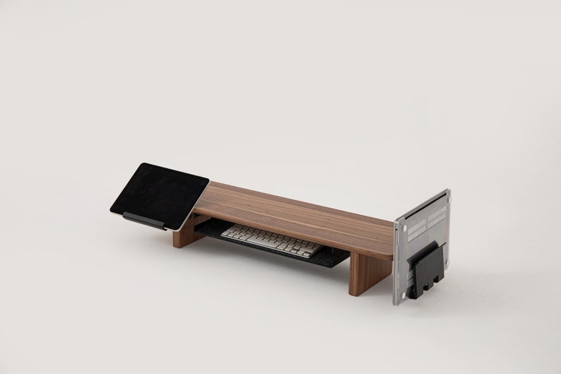 K&ouml;nnte beinhalten: Ein Laptop-St&auml;nder aus Holz mit einem ausziehbaren Tastaturablage und einem Tablethalter. Der St&auml;nder ist aus dunklem Holz und hat ein modernes Design.