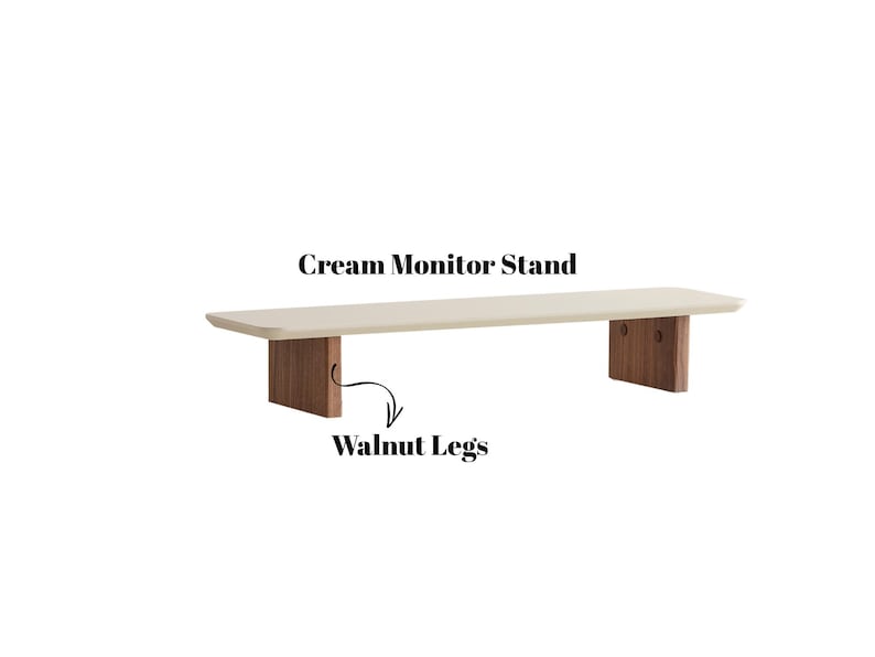 Puede incluir: Soporte de monitor color crema con patas de nogal. El soporte tiene una parte superior rectangular y dos patas rectangulares. El texto "Cream Monitor Stand" y "Walnut Legs" son visibles en la imagen.