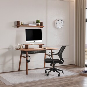 May include: A wooden desk with a monitor stand, a black mesh office chair, and a wall-mounted shelf. The desk features a dark wood finish, a black perforated modesty panel, and a headphone hook. A computer monitor sits on the stand.