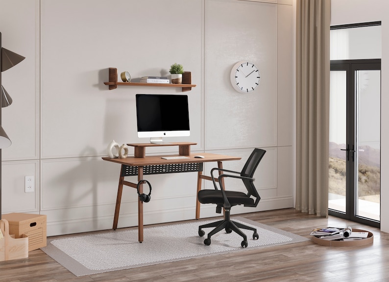May include: A wooden desk with a monitor stand, a black mesh office chair, and a wall-mounted shelf. The desk features a dark wood finish, a black perforated modesty panel, and a headphone hook. A computer monitor sits on the stand.