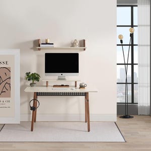 Puede incluir: Una moderna configuraci&oacute;n de oficina en casa con un escritorio blanco con patas de madera, una computadora y un soporte para monitor. Una impresi&oacute;n enmarcada de Matisse, una l&aacute;mpara de pie y una peque&ntilde;a planta se suman a la decoraci&oacute;n. Una alfombra y una estanter&iacute;a completan la habitaci&oacute;n.