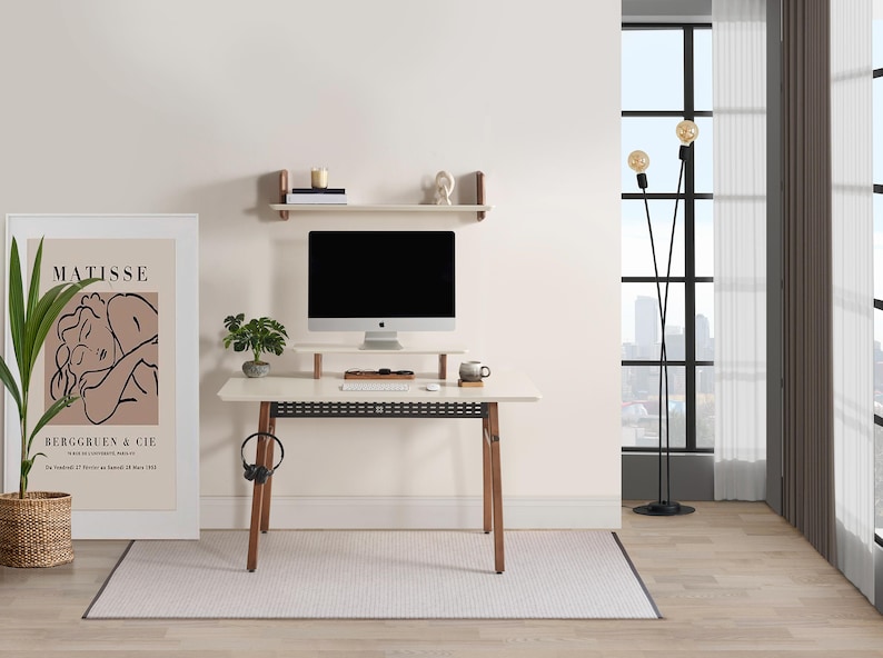 Puede incluir: Una moderna configuraci&oacute;n de oficina en casa con un escritorio blanco con patas de madera, una computadora y un soporte para monitor. Una impresi&oacute;n enmarcada de Matisse, una l&aacute;mpara de pie y una peque&ntilde;a planta se suman a la decoraci&oacute;n. Una alfombra y una estanter&iacute;a completan la habitaci&oacute;n.