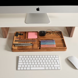 Puede incluir: Organizador de escritorio de madera con compartimentos para material de oficina, bol&iacute;grafos y notas adhesivas. Incluye una regla, bol&iacute;grafos y un juego de rotuladores de colores. Un monitor de ordenador se encuentra encima del organizador, con un teclado y un rat&oacute;n en primer plano.