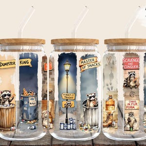 Könnte beinhalten: Drei 473 ml Glas-Dosenhüllen mit Waschbären und humorvollen Sprüchen. Die erste Dosenhülle sagt "Müllkönig" und zeigt einen Waschbären in einer Mülltonne. Die zweite Dosenhülle sagt "Meister der Snacks" und zeigt einen Waschbären, der ein Pizzastück hält. Die dritte Dosenhülle sagt "Plündern und Erobern" und zeigt einen Waschbären, der einen Hotdog hält.