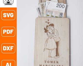 Könnte beinhalten: Ein Holzbrett zum Schneiden mit einem Schlitz zum Aufbewahren von Geld. Das Brett ist mit einem sich küssenden Paar und dem Text "Tomek Marcelina 20.06.2023" graviert.