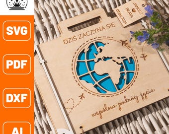 Könnte beinhalten: Holzkoffer-förmige Andenkenbox mit einem lasergeschnittenen Globus-Design und dem Text "DZIŚ ZACZYNA SIĘ" und "wspólna podróż życia". Das Innere des Globus ist blau. Ein Anhänger liest "Janusz Beata 07.06.2024".