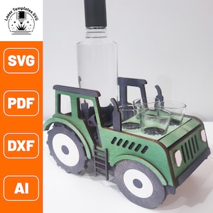 Könnte beinhalten: Grüner, traktorförmiger Flaschenhalter aus Holz mit einer durchsichtigen Glasflasche und vier Schnapsgläsern. Der Traktor hat weiße Räder und eine Leiter an der Seite.
