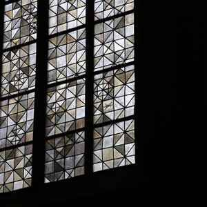 May include: A stained glass window with a geometric pattern of small squares and triangles in shades of brown, gray, and white.