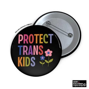 May include: A black button with the text "PROTECT TRANS KIDS" in rainbow colors. Two stylized flowers are below the text.