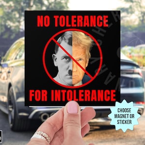 May include: A black and red square sticker with the text "NO TOLERANCE FOR INTOLERANCE". The sticker features a red circle with a diagonal line through it, and the faces of Adolf Hitler and Donald Trump are superimposed on each other within the circle. The sticker is being held in a hand.