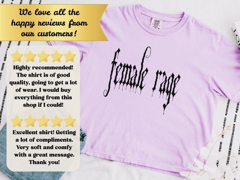 May include: A light purple t-shirt with the words "female rage" in a gothic font. The shirt has a crew neck and short sleeves. The image also includes customer reviews.