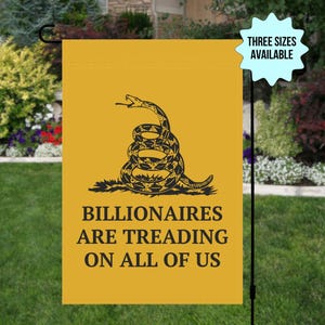 May include: Yellow garden flag featuring a coiled snake illustration with the words "BILLIONAIRES ARE TREADING ON ALL OF US" in black. A light blue starburst graphic states "THREE SIZES AVAILABLE". The flag is displayed outdoors in a garden setting.