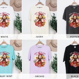 May include: A collection of t-shirts in various colors, including white, ivory, pepper, chalky mint, orchid, and black. Each shirt features a graphic of a person surrounded by flowers, with the text "girls will be girls" above the image.