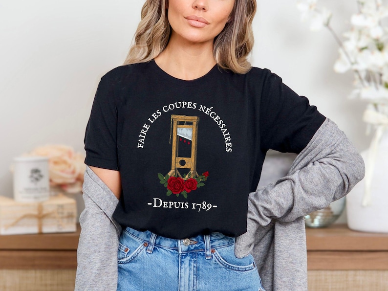 Puede incluir: Camiseta negra con un gr&aacute;fico blanco de una guillotina con rosas y el texto "Faire les coupes necessaires - Depuis 1789 - "