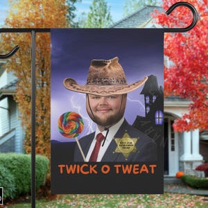 Puede incluir: Bandera de jardín negra con un hombre con sombrero de vaquero sosteniendo una piruleta. La bandera tiene el texto "TWICK O TWEAT" y una placa de sheriff. Una casa embrujada y relámpagos en el fondo.