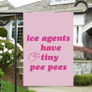 May include: A pink garden flag with the text "ice agents have tiny pee pees" in a bubble font. A hand graphic is included. The flag is hanging outside a house.