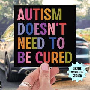 May include: A black square magnet or sticker with the text "AUTISM DOESN'T NEED TO BE CURED" in colorful letters. The image includes a small logo in the bottom left corner and a "CHOOSE MAGNET OR STICKER" graphic.