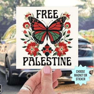 以下が含まれることがあります： 「FREE PALESTINE」の文字が黒で書かれた正方形のステッカーまたはマグネット。赤、緑、クリーム色の蝶と花の模様が描かれています。ステッカーは車の前で手に持たれています。