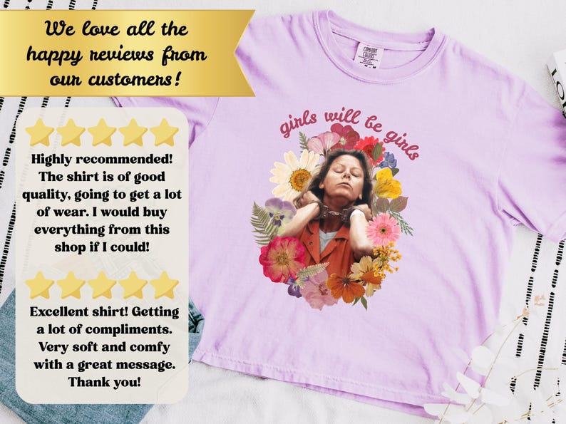 May include: Light purple t-shirt with the phrase "girls will be girls" in pink script. The shirt features a floral design with an image of a person. The shirt has a round neckline.