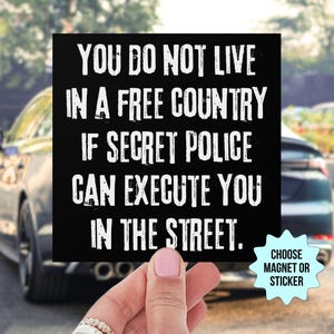 May include: Black square magnet or sticker with white text: "YOU DO NOT LIVE IN A FREE COUNTRY IF SECRET POLICE CAN EXECUTE YOU IN THE STREET." A light blue starburst graphic says "CHOOSE MAGNET OR STICKER".