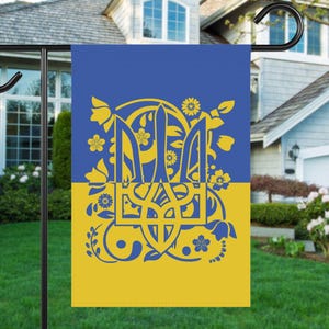 Könnte beinhalten: Eine gelbe und blaue Gartenflagge mit einem stilisierten ukrainischen Dreizack-Design. Der Dreizack ist von floralen Mustern umgeben.