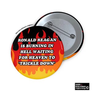 以下が含まれることがあります： 赤い背景と黄色の炎がついた丸いボタン。ボタンのテキストは「RONALD REAGAN IS BURNING IN HELL WAITING FOR HEAVEN TO "TRICKLE DOWN"」です