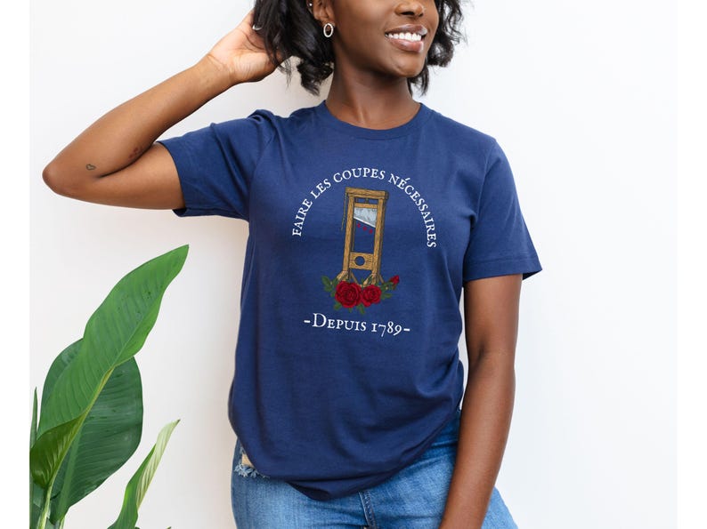 Puede incluir: Una camiseta azul marino con un gr&aacute;fico blanco de una guillotina con el texto "Faire les coupes n&eacute;cessaires - Depuis 1789 -"