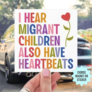 May include: A square magnet or sticker featuring the multi-colored text I HEAR MIGRANT CHILDREN ALSO HAVE HEARTBEATS and a red heart-shaped flower on a green stem. A light blue starburst graphic in the corner reads CHOOSE MAGNET OR STICKER.