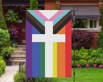 May include: A garden flag with a white cross on a background of rainbow stripes, including purple, blue, green, yellow, orange, and red. The cross is superimposed on a brown, blue, and pink triangle.