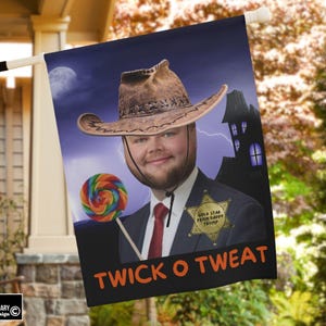 Può includere: Bandiera decorativa da esterno con un uomo con cappello da cowboy e completo, che tiene in mano un lecca lecca. La bandiera ha uno sfondo blu scuro con luna piena, fulmini e una casa stregata. Il testo recita "TWICK O TWEAT".