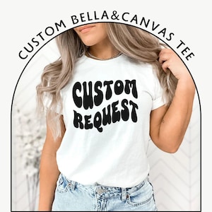 Può includere: Maglietta bianca con testo nero che recita "CUSTOM REQUEST" in un font retrò e ondulato.