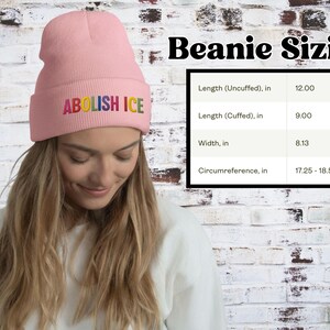 May include: A light pink beanie with the embroidered text "ABOLISH ICE" in rainbow colors. The beanie's dimensions are: 12 inches long uncuffed, 9 inches long cuffed, 8.13 inches wide, and a circumference of 17.25-18.50 inches.