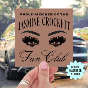 May include: A brown square magnet or sticker featuring the text "PROUD MEMBER OF THE JASMINE CROCKETT FAN CLUB" and an illustration of eyes with long eyelashes. A blue starburst in the corner says "CHOOSE MAGNET OR STICKER".