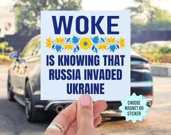 May include: A blue and yellow floral design surrounds the text "WOKE IS KNOWING THAT RUSSIA INVADED UKRAINE". The text is in bold, blue font. The background is light blue. The image is a sticker or magnet.