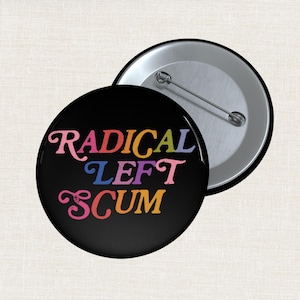 May include: A black button with the words "RADICAL LEFT SCUM" in colorful, stylized lettering. The button is round with a pin back, and another button is partially visible.