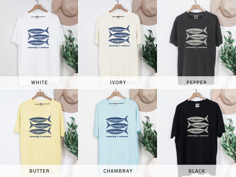 May include: A set of ten t-shirts in various colors, each featuring a graphic of three fish with the text "community is resilience". The colors include white, ivory, pepper, butter, and Chambray.