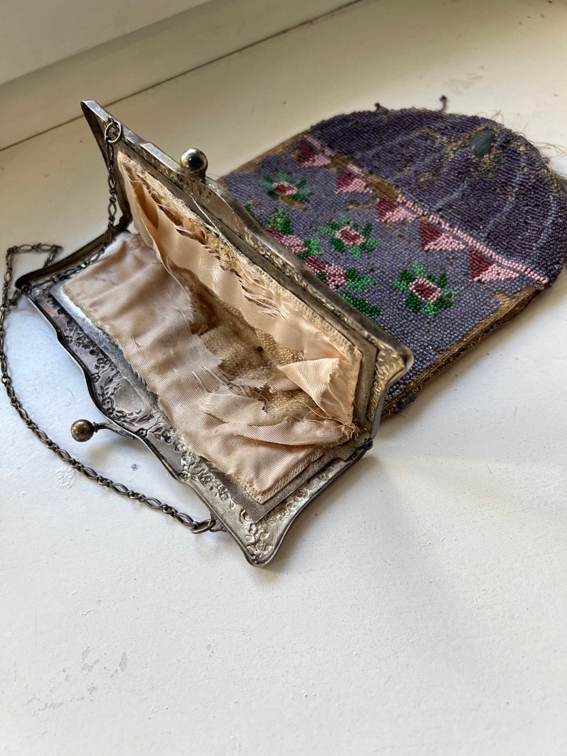 May include: A vintage beaded purse with a silver frame and a chain strap. The purse is open, revealing a pink satin lining.