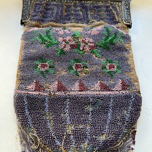 May include: A vintage beaded purse with a silver clasp and floral design. The purse is made of small, purple beads and has a fringe of beads hanging from the bottom.