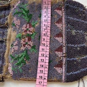 May include: A beaded purse with a floral design in shades of pink, green, and purple. The purse is approximately 17 inches long and has a silver clasp.