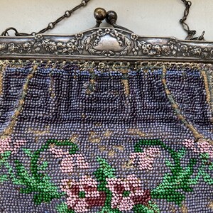 May include: A vintage beaded purse with a silver frame and floral design. The purse is made of small, colorful beads and features a floral pattern with pink, green, and purple beads.