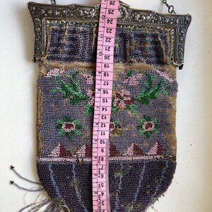 May include: A beaded purse with a silver frame and a chain strap. The purse is decorated with floral designs in shades of pink, green, and purple. The purse measures approximately 28 inches in length.